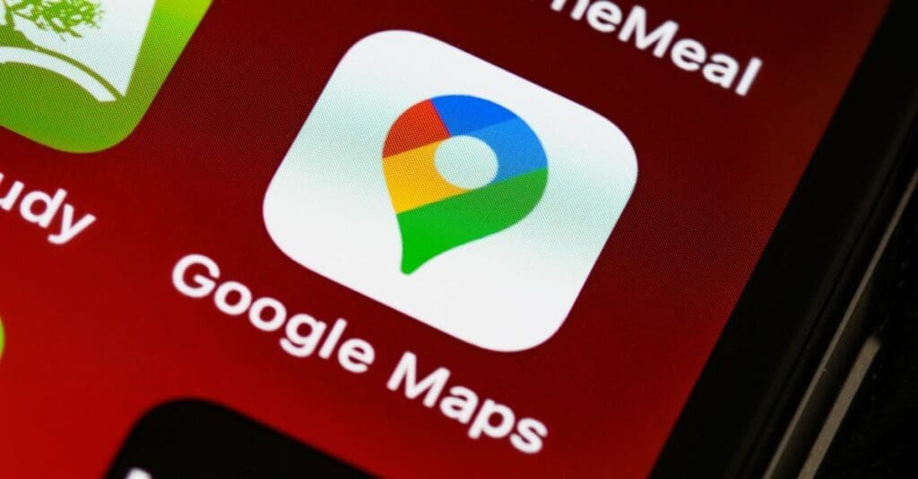 Close-up of the Google Maps app icon on a red smartphone home screen, featuring a white rounded square with a multicolor map pin.